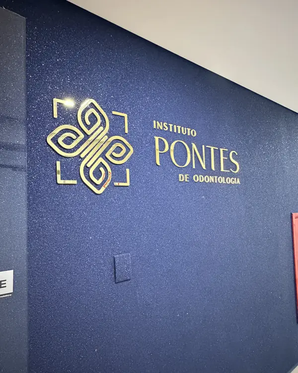 Parede azul da entrada com o logotipo dourado do Instituto de Odontologia Pontes.
